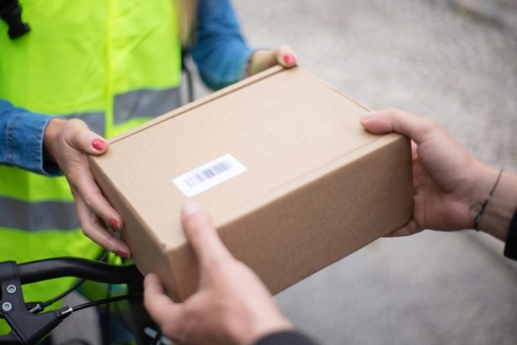 Close-up of hands exchanging a cardboard box outdoors, symbolizing delivery service in Portugal.